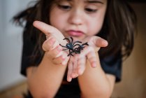 Chica sosteniendo dos arañas falsas - foto de stock
