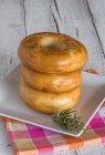 Stack of fresh bagels on ceramic plate with herbs — Stock Photo