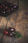 Tre ciliegie mature fresche con foglie su legno scuro — Foto stock