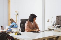 Жінка сидить на робочому місці і використовує комп'ютер — стокове фото