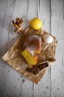 Flache Ansicht von Zitronenkuchen mit Zutaten auf Backpapier über weißem Bauerntisch — Stockfoto