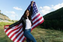 Щасливі брюнетка жінка позує з прапором США — стокове фото