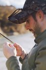 Retrato de homem sereno preparando gancho para a pesca no rio — Fotografia de Stock