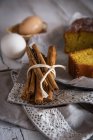 Close up view of tied with rural string pile of cinnamon sticks on towel near homemade cake and eggs on background — Stock Photo