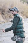 Вид збоку на людину, що стоїть біля річки і риболовля зі стрижнем в осінній день — стокове фото