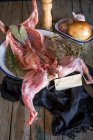 Carcassa di coniglio crudo con ingredienti e targhetta su tavola di legno — Foto stock