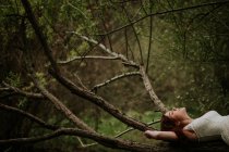 Crop rilassato ragazza sdraiata su ramo d'albero — Foto stock