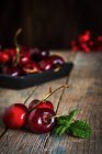 Still life of cherries and mint leaves on wooden table — Stock Photo