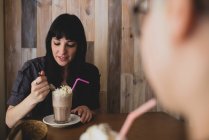Brunette woman eating milk shake — Stock Photo