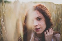 Close up portrait of girl with red hair posing in rye field and looking at camera — Stock Photo