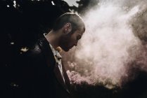 Vista lateral do homem posando com vela de fumaça na floresta — Fotografia de Stock