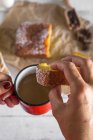 Above view of female hands holding mug of hot chocolate and slice of homemade cake — Stock Photo
