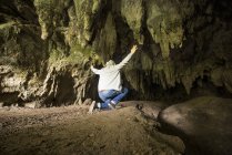 Visão traseira do homem com braços erguidos na caverna — Fotografia de Stock