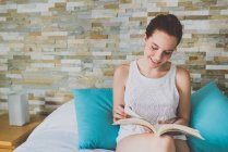 Menina sentada na cama e livro de leitura — Fotografia de Stock