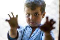 Árabe chico mirando a la cámara y sosteniendo rejilla - foto de stock