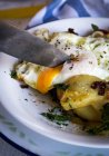 Close up knife slicing fried egg and potatoes — Stock Photo