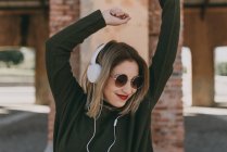 Chica en auriculares posando con los brazos levantados - foto de stock