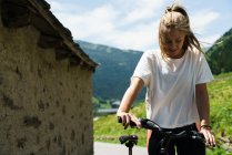 Ragazza bionda a piedi con la bicicletta in campagna di montagna — Foto stock