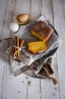 High angle view of lemon cake with ingredients on bakery paper over white rural table — Stock Photo