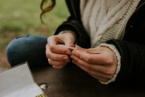 Cultivo manos femeninas rodando cigarrillo en el césped - foto de stock