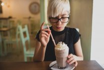 Девушка в очках пьет молочный коктейль — стоковое фото