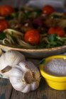 Чесночные луковицы и соль перед спагетти и фрикадельки украшены листьями базилика и помидоры на гриле на блюдечке — стоковое фото