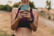 Спортсменка використовує свій смартфон у парку після тренування — стокове фото