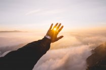 Hand closing sun on background of clouds. — Stock Photo
