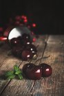 Fresh ripe cherries scattered on dark wood — Stock Photo