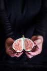 Mains féminines tenant fig frais coupé en deux — Photo de stock