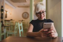 Девушка с помощью смартфона в кафе — стоковое фото