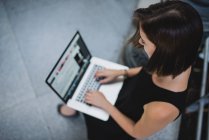 High angle portrait of brunette girl using laptop on her knees — Stock Photo