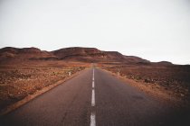 Strada asfaltata vuota che attraversa le terre desolate . — Foto stock