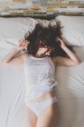 Жінка з волоссям на обличчі лежить на ліжку — стокове фото