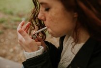 Crop zenzero ragazza con lentiggini accendendo sigaretta — Foto stock