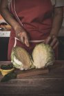 Midsection of woman slicing cabbage on wooden board — Stock Photo
