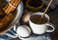 Крупный план яиц и чашки с ложкой меда на деревенском полотенце — стоковое фото