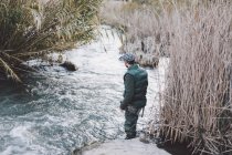 Rückansicht eines Fischers, der am Ufer steht und auf den Fluss blickt — Stockfoto