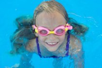 Дитина в окулярах в плаванні біля басейну і дивиться на камеру — стокове фото