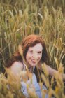 Ritratto di felice testa rossa sorridente ragazza seduta in segale e guardando la macchina fotografica — Foto stock