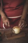 Midsection of woman slicing onion on wooden board — Stock Photo