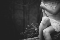 Crop sensual girl sitting on tree and touching shoulder — Stock Photo