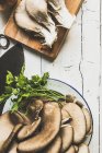 Top view of pleurotus mushrooms on plate with parsley and wooden board — Stock Photo