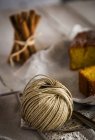 Vista de cerca de madeja de hilo rural en la mesa con torta y palitos de canela - foto de stock