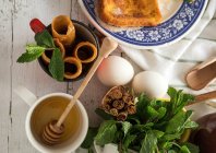 Top view of table with fried honey dough tubes with mint leaves, eggs and cinnamon tubes — Stock Photo