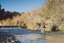 Fischer werfen Ausrüstung in den Fluss. in sonniger Landschaft — Stockfoto