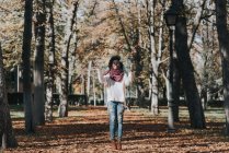 Портрет счастливой девушки, бросающей осеннюю листву в воздух в парке в солнечный день — стоковое фото
