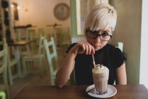 Девушка в очках пьет молочный коктейль — стоковое фото