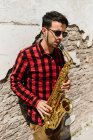 Jazzman appuyé sur un mur de briques et jouant sur du saxophone — Photo de stock