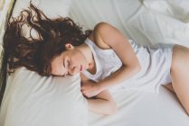 Schöne Frau schläft auf weißem Bett — Stockfoto